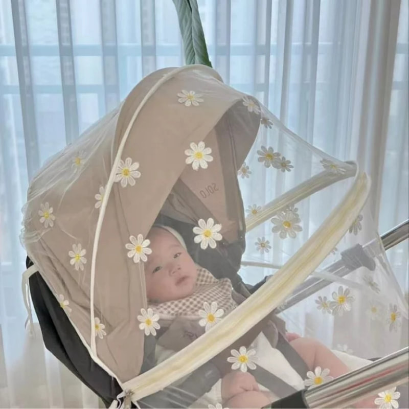 baby sitting in a stroller mosquito net